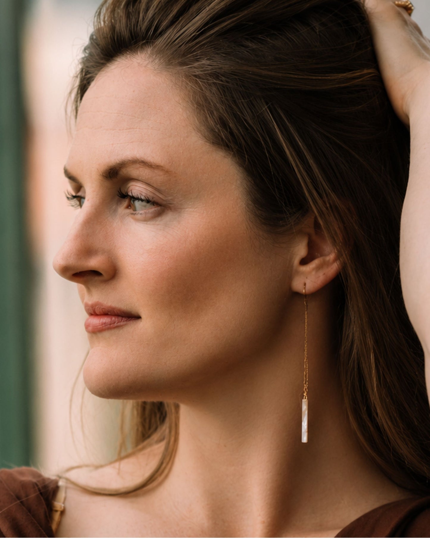 The Mallory gold and natural seashell pull-through earrings shown on model — Olivia Holland
